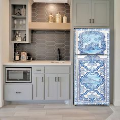 a blue and white tile refrigerator freezer sitting inside of a kitchen next to cabinets