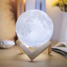 a white moon lamp sitting on top of a wooden table next to an open book