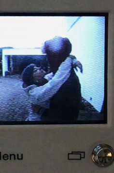 a man and woman hugging each other in front of a tv screen with the word menu on it