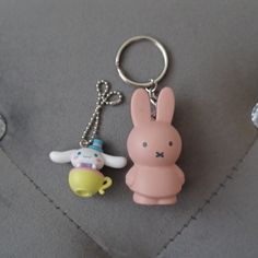 two keychains with cartoon characters on them sitting on a table next to each other