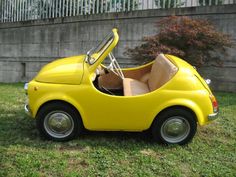 a small yellow car is parked in the grass