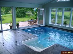 an indoor swimming pool with sliding glass doors leading out to the backyard and patio area