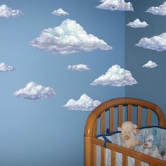 there is a crib in the room with clouds on the wall and teddy bears