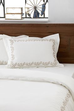 a bed with white sheets and pillows in front of a window