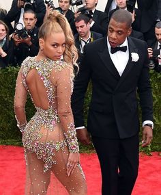 a man in a tuxedo standing next to a woman in a sheer dress