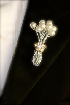 a brooch with pearls on it sitting on a black suit lapel collar pin