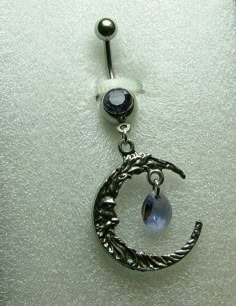 an image of a belly ring with a blue stone in the center and a crescent charm hanging from it