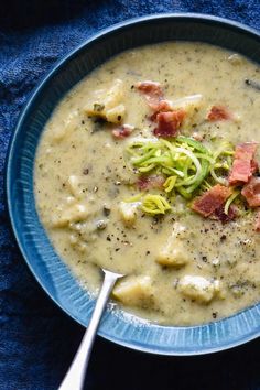 a bowl of soup with broccoli and bacon in it on a blue cloth