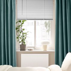 a bedroom with blue curtains and a white radiator next to the windowsill