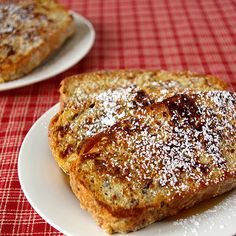 two white plates topped with french toast and powdered sugar