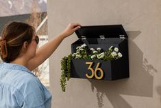 a woman placing flowers in a mailbox