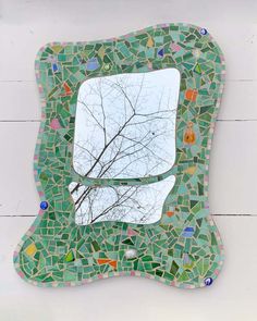 a mirror that is sitting on the side of a wall with a tree in it