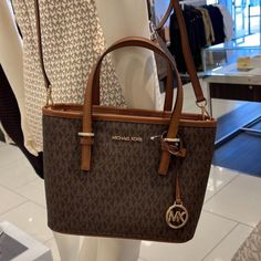 Michael Kors Jet Set Travel Xs Carryall Tote Top Zip Tote Brown Color: Brown Gold Toned Hardware Zip Top Closure Slip-In Pocket One Mk Charm Custom Fabric Lining 1 Slip-In Pocket, 1 Zipper Pocket 9"(Top) 11"(Bottom) X 7.75" (H) X 4.25"(D) Strap: 5", 24" Purse Charms Diy, Michael Kors Clothes, Michael Kors Tote Bags, Carryall Tote, Blue Tote, House Decorating, Coach Shoulder Bag, Zip Tote, Black Leather Tote