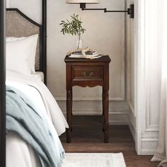 a bed room with a neatly made bed and a lamp on the end table next to it