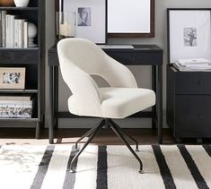 a white chair sitting in front of a desk with bookshelves and pictures on it