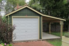 a garage with a brick walkway in front of it and a green shed behind it