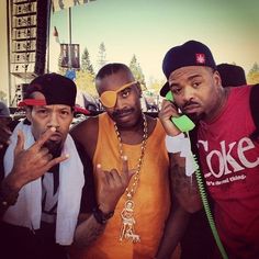 three men standing next to each other while talking on cell phones