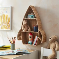 a stuffed bear is sitting next to a shelf with books, toys and other items