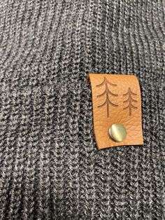 Give the gift of warmth and style! This knit beanie is perfect for hiking, camping, and perfect for keeping warm! Beanie is a dark charcoal gray color, and is made of a soft wool/acrylic blend. Attached is an engraved leather label tag with a brass rivet. The leather label is engraved on both sides, so whether you wear the hat with the brim up or down, the label will still show the design in the correct orientation. Choice of circle logo or trees available at checkout. Care - Hand wash, dry flat Gray Warm Beanie For Outdoor, Warm Gray Beanie For Outdoor, Warm Gray Hats For Outdoor, Warm Gray Hat For Outdoor, Winter Beanie For Outdoor Wear, Winter Knitted Beanie For Outdoor, Knitted Beanie For Winter Outdoor Wear, Gray Hats For Winter Outdoor Activities, Warm Hat For Outdoor Fall Use