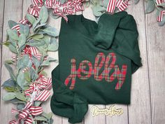 a green shirt with the word noel on it and some red and white ribbons around it