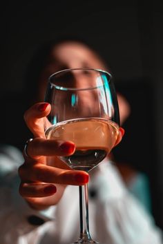 a woman holding a glass of wine in her hand