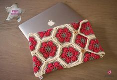 a red and white crocheted purse sitting on top of a wooden table