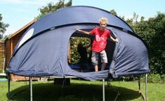 a young boy is standing in the inside of a blue tent with its door open