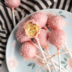 pink cake pops with white sprinkles are on a blue and white plate