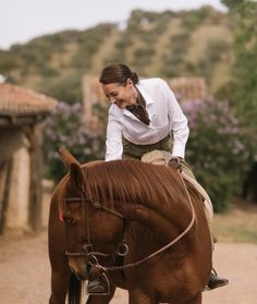 a woman riding on the back of a brown horse