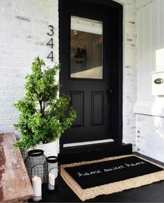 a black front door with a welcome mat and potted plant next to it on the porch