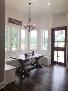 a dining room table and bench in front of windows with wood flooring on both sides