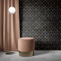 a modern floor lamp in front of a black and gold geometric wallpaper with a round foot stool next to it