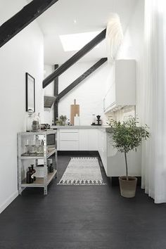 a kitchen with black and white flooring next to a plant in a pot on top of a shelf