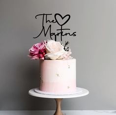 there is a pink cake with flowers on the top that says the martinis and it's written in black