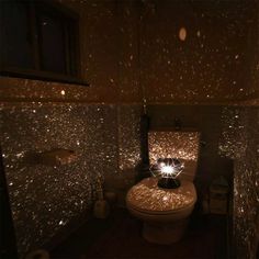 a toilet with some lights on it in a room that is dimly lit and has stars all over the walls