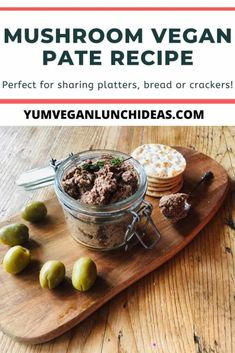 a wooden cutting board topped with olives next to a jar filled with meat and cheese