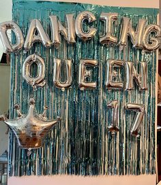 a sign that says dancing queen with balloons hanging from it's sides in front of a wall