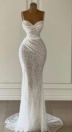 a white wedding dress on a mannequin stand in front of a wall and floor