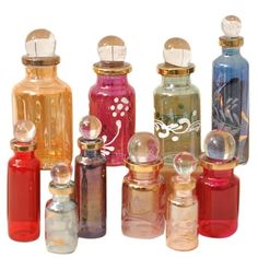 an assortment of colorful glass bottles are lined up in a row on a white background