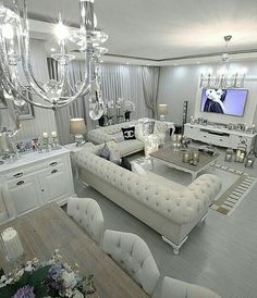 a living room filled with white furniture and chandelier