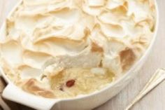 a white dish filled with whipped cream next to two spoons