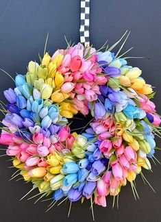 a multicolored wreath hanging on a door with grass and flowers in the center