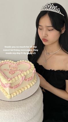 a woman in a tiara is looking at a heart shaped cake