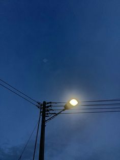 the street light is lit up in the dark sky at night with power lines and telephone poles