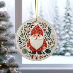 a christmas ornament hanging from a tree in front of a snow covered window