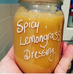 a hand holding a jar with some liquid in it that says spicy lemongrass dressing