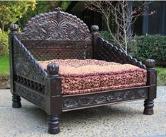 an ornate wooden bed frame with pink and gold fabric on it's headboard