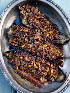 stuffed eggplant with chili and pine nuts in a silver bowl on a blue surface