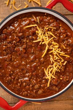 chili and cheese in a red pot on a wooden table