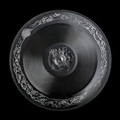 a black and white photo of an old record with intricate designs on the side, taken from above